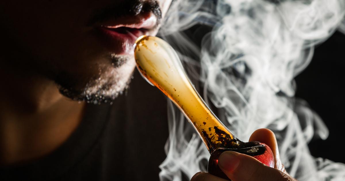 man smoking marijuana with glass pipe